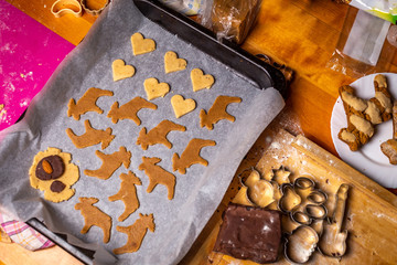 Baking traditional Czech Christmas gingerbread, pan with baking paper, forms, cutters, dough and other ingredients on the wooden table, top view