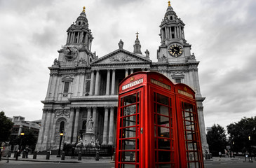 st paul cathedral on the background and two red telephone booths in London at cloudy day. Black and white picture with two red telephone boxes.