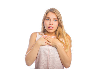 A young beautiful blonde woman holds both her arms on her chest and shows that she is concerned, shooting close-ups on an isolated background