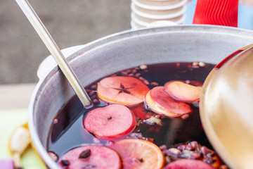 Mulled wine prepared in iron pot at city street fair. Traditional christmas and new year alcohol drink - hot wine. Stall with drinks in town at winter holiday fest