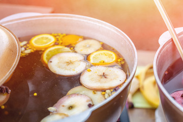 Mulled wine prepared in iron pot at city street fair. Traditional christmas and new year alcohol drink - hot wine. Stall with drinks in town at winter holiday fest