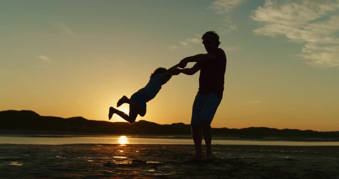 Silhouette Of Father And Son Playing Together At The Beach.