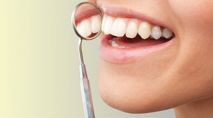 Woman teeth and a dentist mouth mirror on background