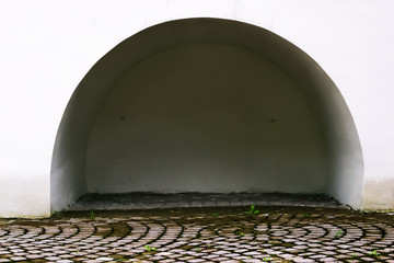 A semicircular alcove in the white wall. Paved sidewalk. Footpath.
