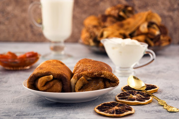 Two rolls of fried pancakes with stuffing. Delicious breakfast. Light wooden background.
