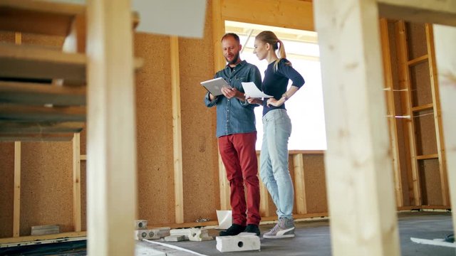 Two young people discussing the construction of a house inside the house. Long shot. Soft focus