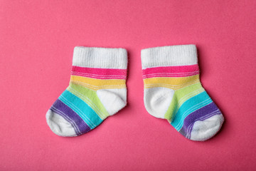 Pair of cute child socks on color background, top view