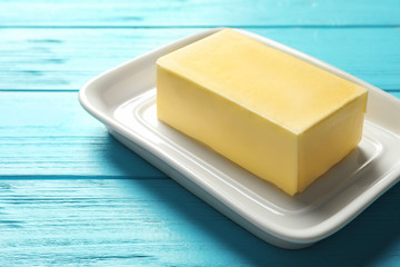 Dish with fresh butter on wooden background, closeup