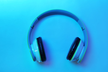 Stylish modern headphones with earmuffs on color background, top view