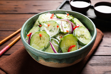 Dish with fresh creamy cucumber salad served on wooden table