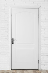 Closed white wooden door in brick wall