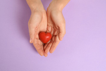 Woman holding decorative heart on color background, top view with space for text