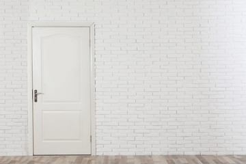Closed white wooden door in brick wall