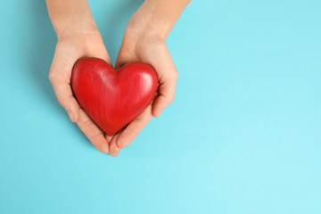 Woman holding decorative heart on color background, top view with space for text