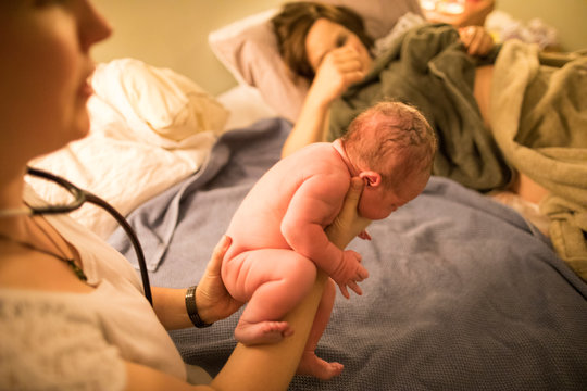 Midwife Examining Newborn Baby In Hospital