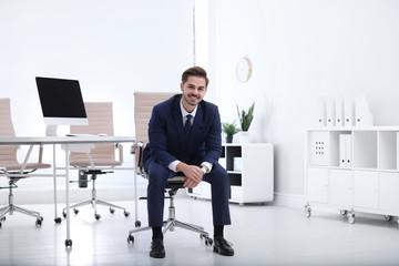 Young businessman sitting on office chair at workplace