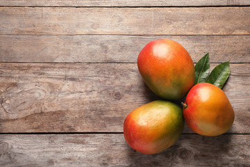 Flat lay composition with mango on wooden background. Space for text