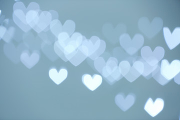 Blurred view of beautiful heart shaped lights on gray background