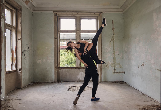 Man lifting ballerina while practicing ballet in old building