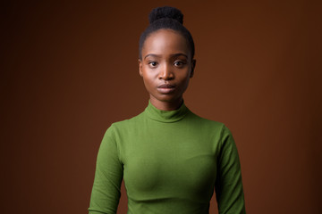 Obraz premium Young beautiful African Zulu businesswoman against brown backgro
