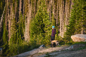 Obraz premium a young woman and her dog standing next to a beautiful mountain lake