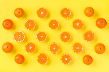 Fruit pattern of fresh mandarin slices on yellow background. Flat lay, top view. Pop art design, creative summer concept. Half of citrus in minimal style. Tangerine.