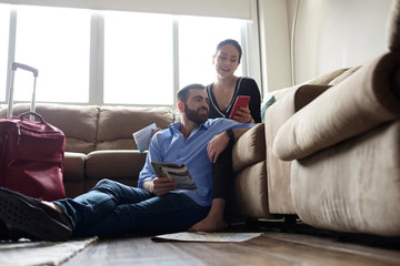 Young couple using mobile phone while sitting in living room at rental house