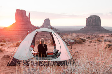 Rear view of woman sitting in tent against sky at Monument Valley Tribal Park during sunset