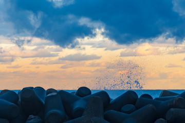 秋の終わりの朝、日本海の夜明けに波がテトラポットに打ち付けられ、波飛沫が泡立つ光景が美しい。