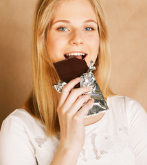 young beauty blond teenage girl eating chocolate smiling