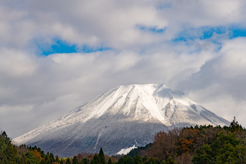 Obraz na płótnie Canvas 秋の終わり、初雪の降った翌日の雲間からの光に照らされる大山の風景が美しい