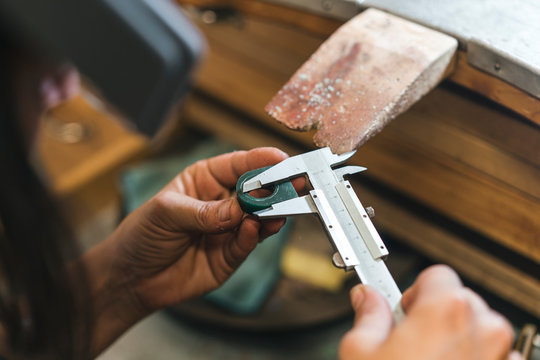 Close up of woman's hands measuring equipment at table in workshop