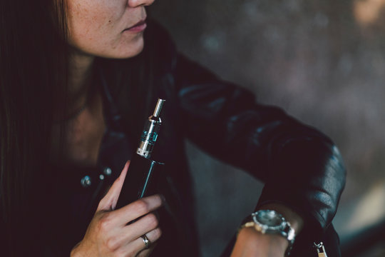 Midsection of young woman holding electronic cigarette