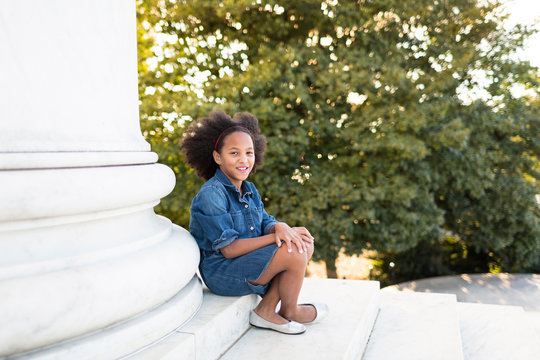 Portrait of smiling girl sitting on steps in park