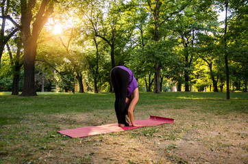 Unrecognizable fit yoga girl doing stretches in park at sunset 