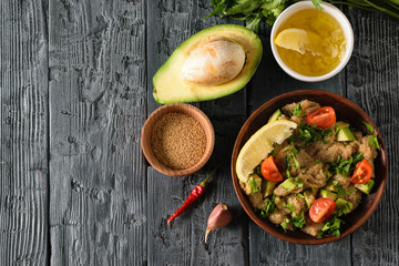 Clay bowl with amaranth seed salad with avocado, lemon, tomatoes and parsley and bowl with amaranth on a dark wooden table. The view from the top.
