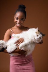 Young beautiful African Zulu woman holding cat while smiling