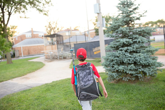 Rear view of baseball player with backpack walking outdoors