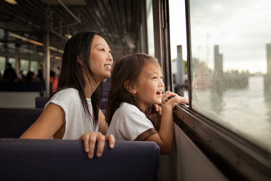 Smiling mother and daughter looking through window in ferry