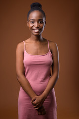 Young beautiful African Zulu woman smiling against brown background
