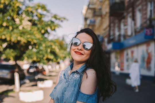 Smiling young woman wearing sunglasses while standing in city