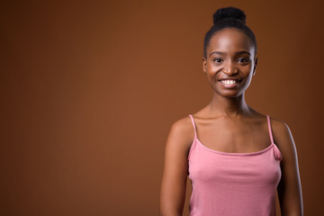 Happy African Zulu woman smiling against brown background