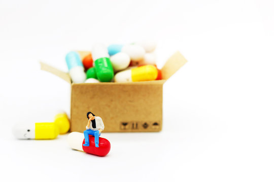 Miniature people: Patients sitting on drugs. Health care and business concept.
