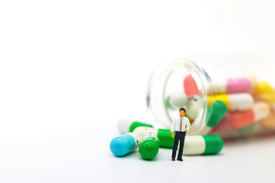 Miniature people: Doctor standing with drugs. Health care and business concept.