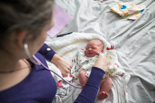 Midwife checking newborn baby at home