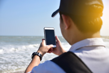 People are holding mobile smart phone at sea  background