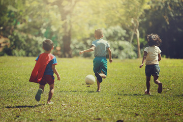 Group of happy children playing with soccer ball on meadow, together concept.