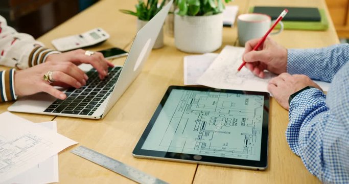 Male And Female Architects Working On Plans In Their Studio