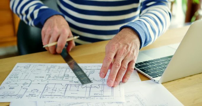 Architect Working On Construction Design Blueprints At His Desk