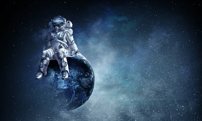 Obraz na płótnie Canvas Astronaut in spacesuit on globe. Mixed media